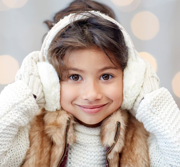 happy little girl in earmuffs over holidays lights